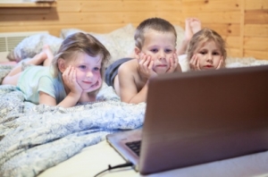 Pretty children looking at computer monitor while laying in bed
